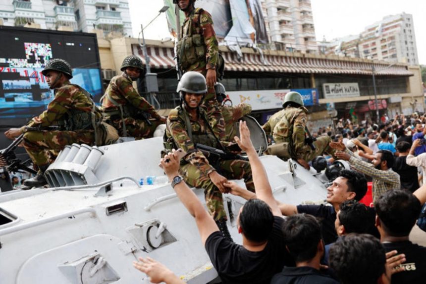 People shake hands with army personnel as they celebrate the resignation of Bangladeshi Prime Minister Sheikh Hasina