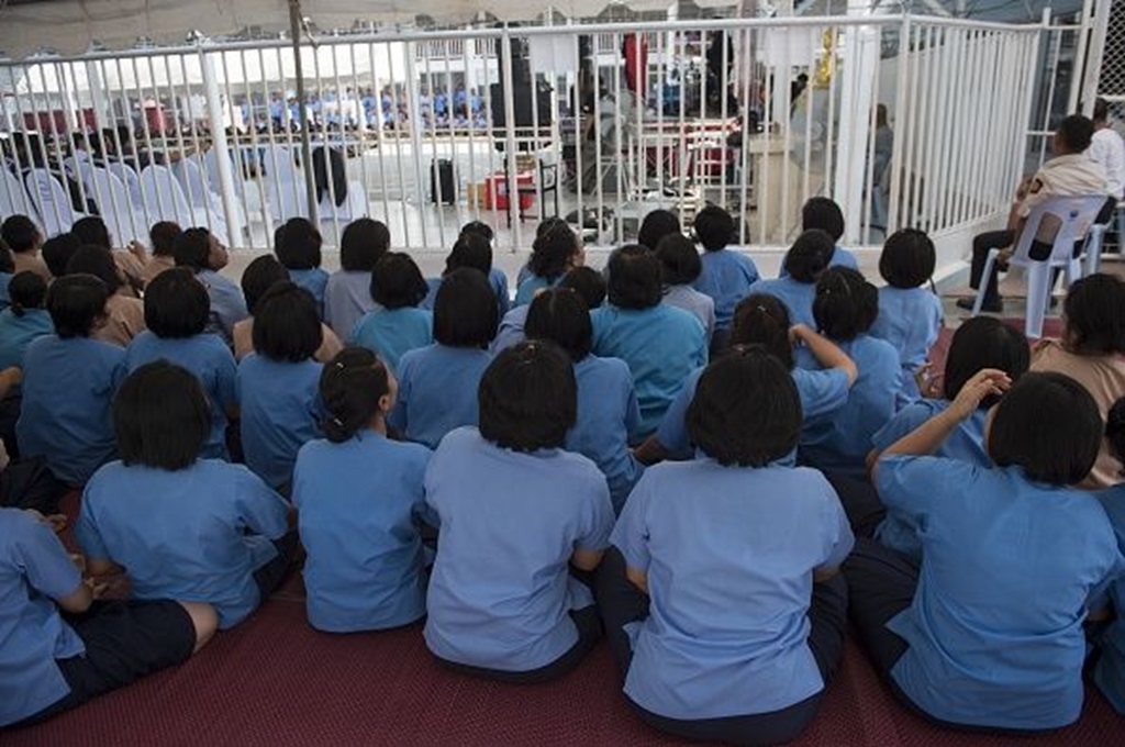  female prison inmates sitting outside the courtyard of a Thai prison. Getty Images