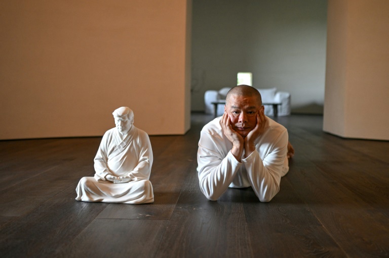 Hong Jinshi poses next to one of his sculptures of US president-elect Donald Trump 